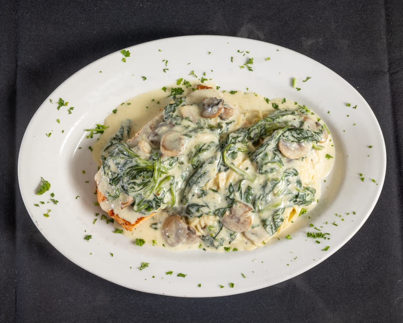 Chicken breast with creamy mushroom and spinach sauce, served over pasta.