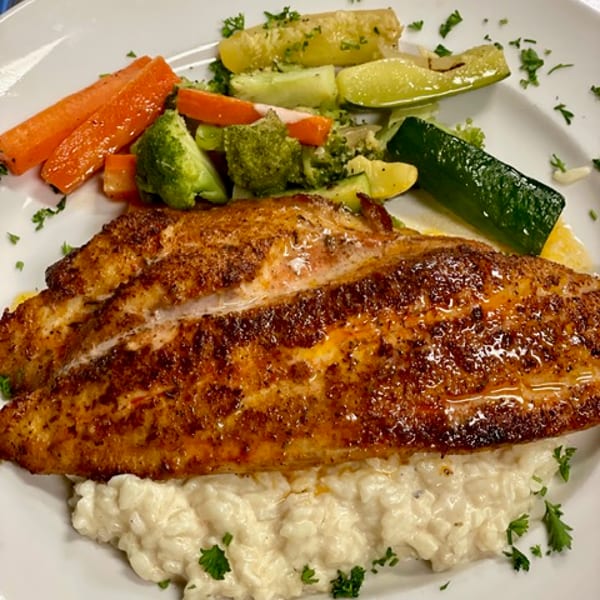 Blackened red snapper over risotto with vegetables
